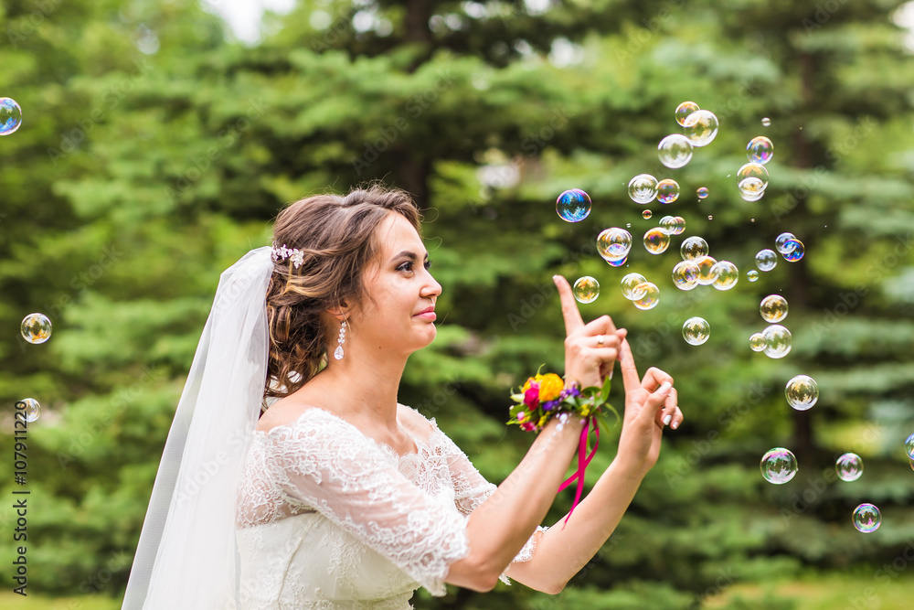 Young bride play with soap-bubble and joy smile