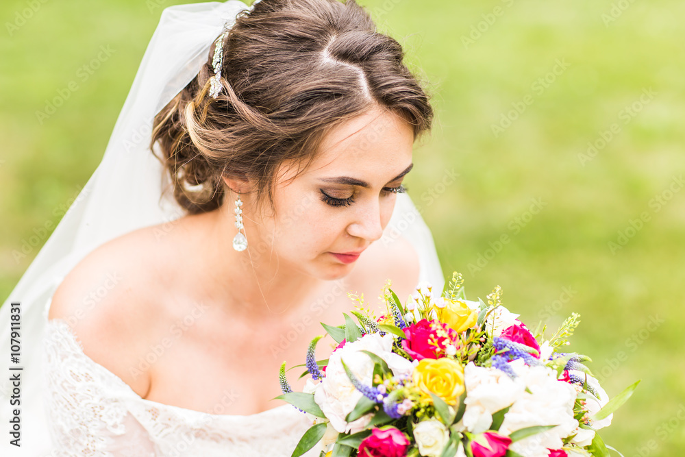 Beautiful bride with wedding bouquet of flowers outdoors in  park.