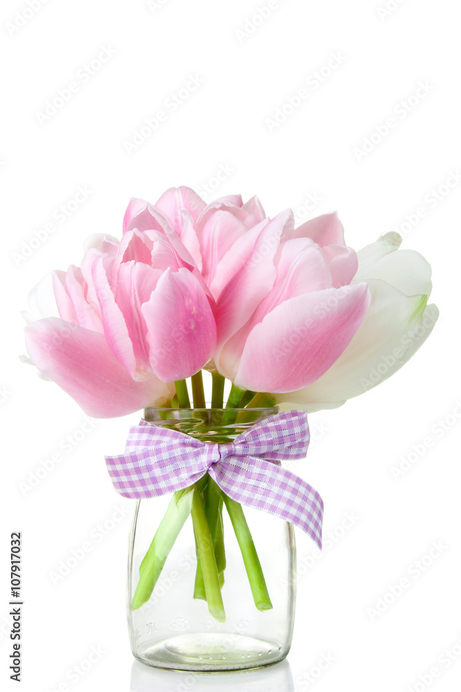 the pink and white tulips in a glass jar with water isolated on white background