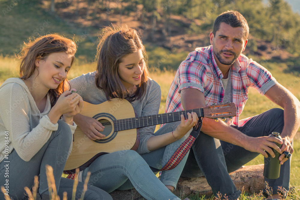 Young woman sing playing guitar with friends on sunset outdoor Young woman sing playing guitar with friends on sunset outdoor