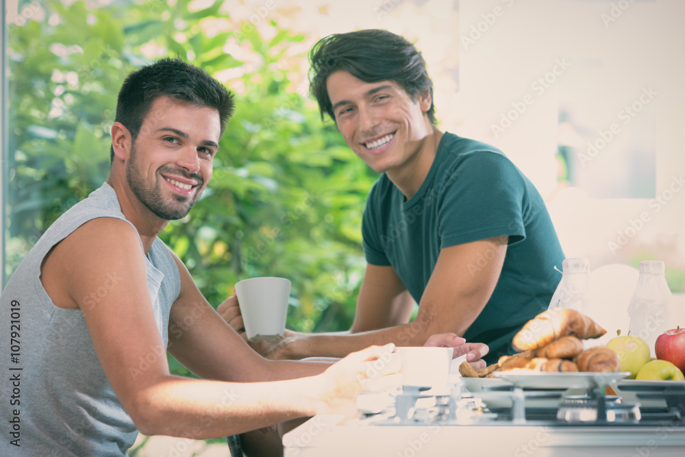 Young gay couple have breakfast in the kitchen in sunny day