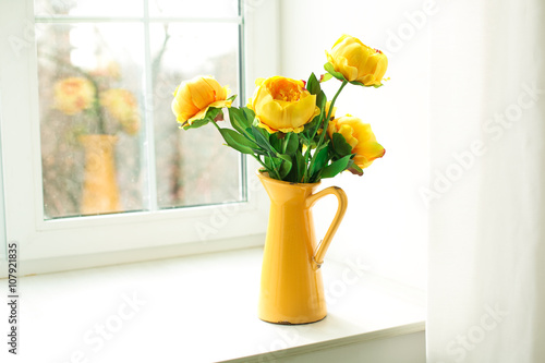 yellow flowers in a yellow vase on a windowsill