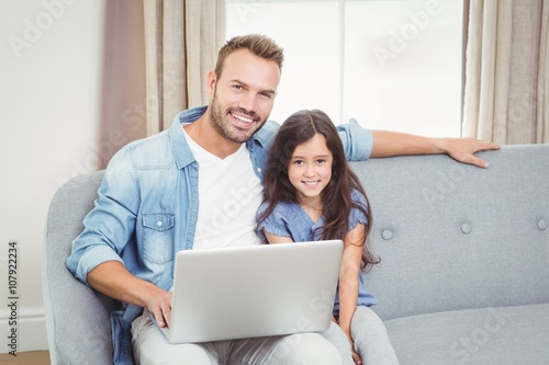 Portrait of cheerful father and daughter using laptop 