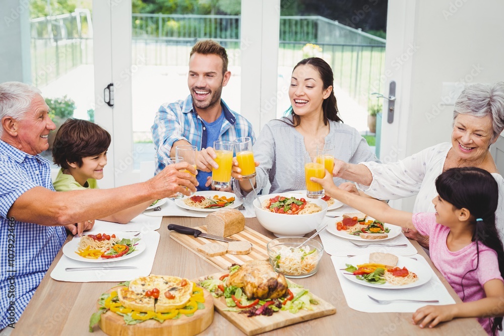 Smiling multi generation family toasting juice 