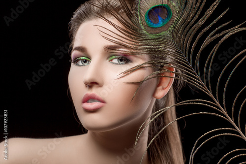 girl with bright  makeup and peacock feathe