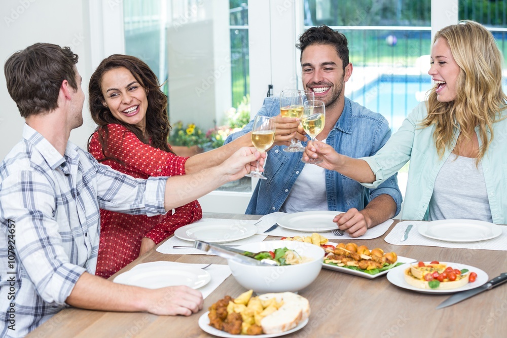 Smiling friends toasting white wine