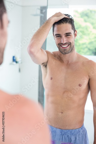 Handsome shirtless man smiling to a mirror