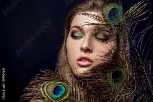 girl with bright  makeup and peacock feathe photo