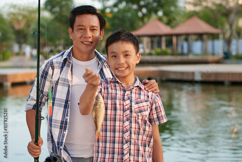 Smiling Asian boy and his proud father showing what they caught