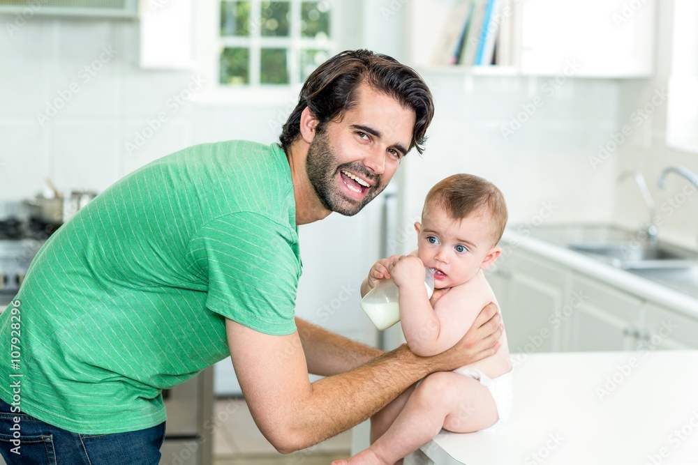 Fototapeta premium Happy father with son drinking milk at kitchen table