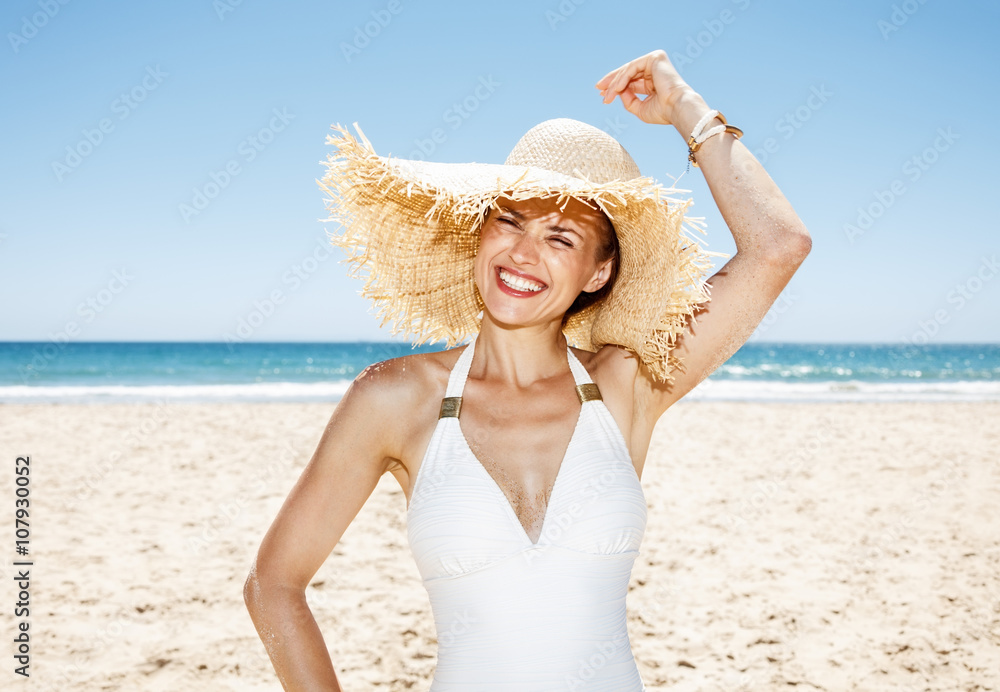 Happy woman in white swimsuit and straw hat at sandy beach Happy woman in white swimsuit and straw hat at sandy beach