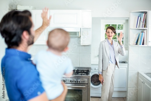 Man waving at wife while carrying son