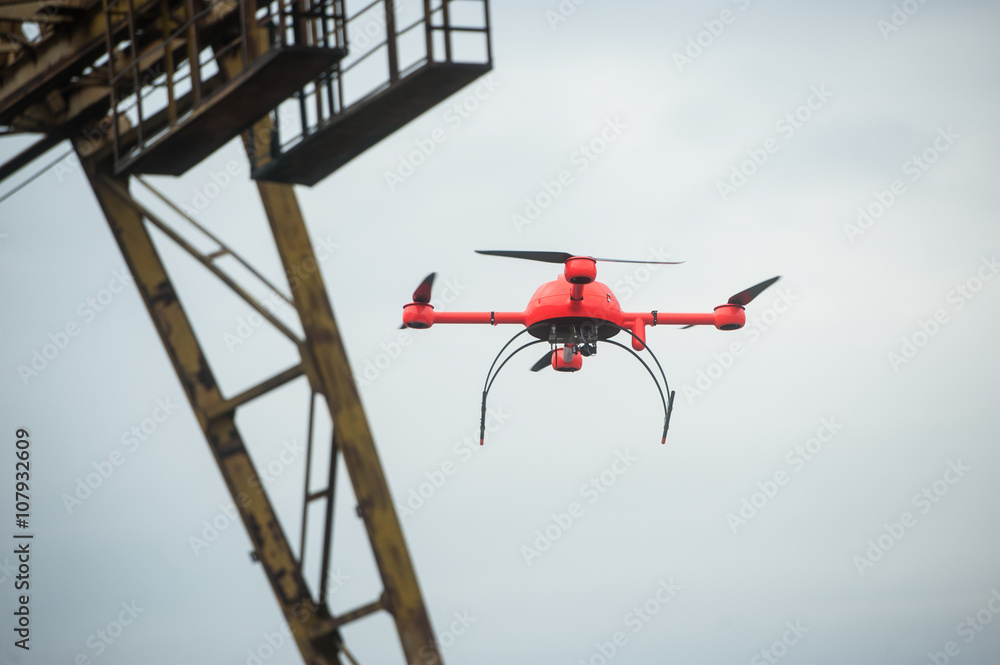 Red industrial drone flies over metal structures industrial faci Red industrial drone flies over metal structures industrial faci