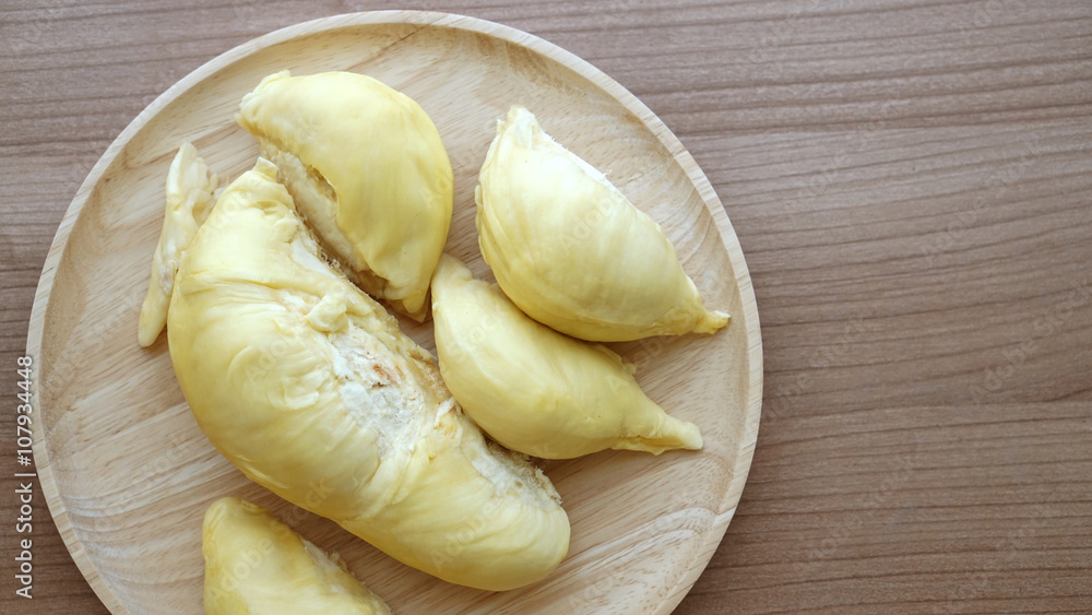 Smelly yellow ripe durian on wood plate. Tropical summer fruit w