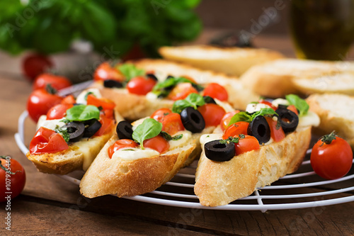 Bruschetta with tomatoes, mozzarella, olives and basil pesto