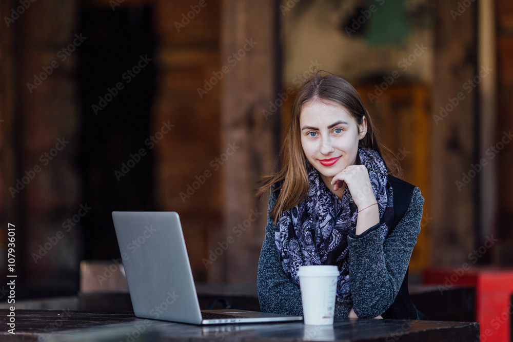 Young girl sitting behind the cafe on her laptop Young girl sitting behind the cafe on her laptop