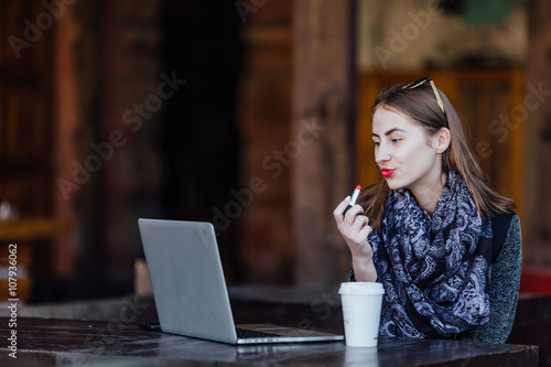 Young girl sitting behind the cafe on her laptop