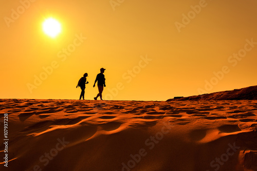 Two people walking on sand desert