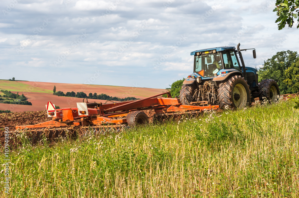 Fototapeta premium Farmer in tractor working on a field