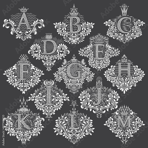 Set of heraldic monograms in coats of arms form. White floral decorative stamps of letters from A to M. Isolated tattoo labels in vintage baroque style.