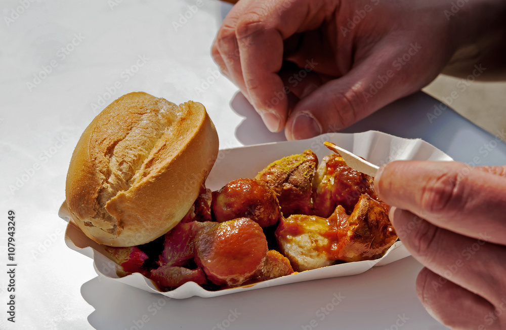 Currywurst in Schale an einem Imbiss, Mann isst eine Currywurst Currywurst in Schale an einem Imbiss, Mann isst eine Currywurst