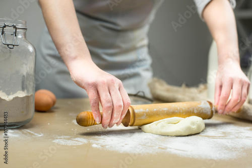 Closeup of female baker's hands kneading dough in bakery.