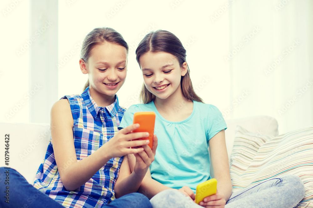 happy girls with smartphones sitting on sofa happy girls with smartphones sitting on sofa