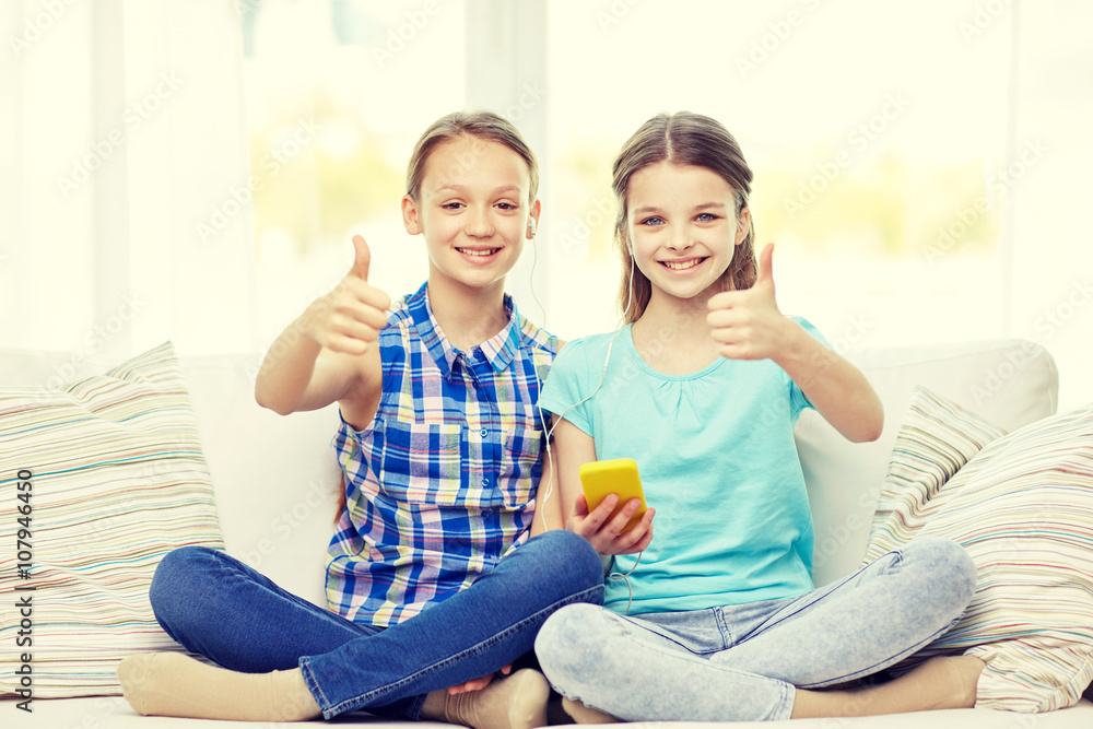 happy girls with smartphone sitting on sofa happy girls with smartphone sitting on sofa