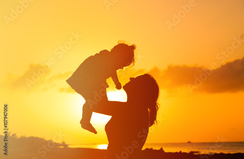 mother and little daughter play at sunset
