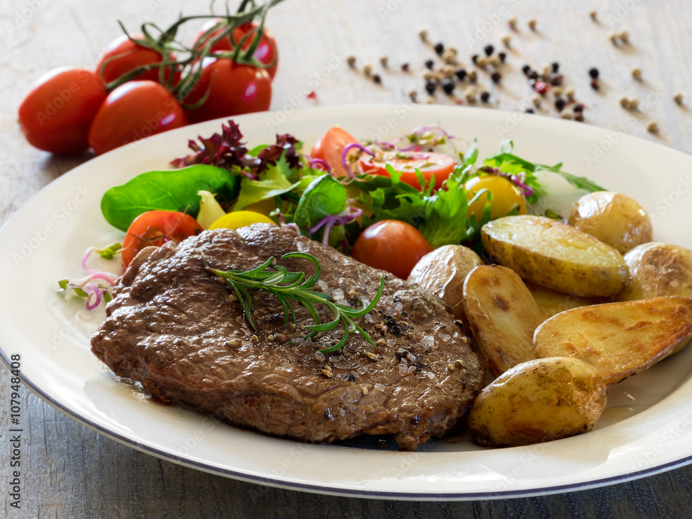 Roasted beef steak with baked potatoes and vegetable salad 