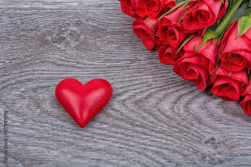 Red roses and heart on a wooden background
