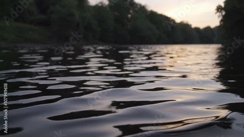 Closeup of river water at sunset in slow motion. Insects interact with the river ripples on a warm summers evening photo