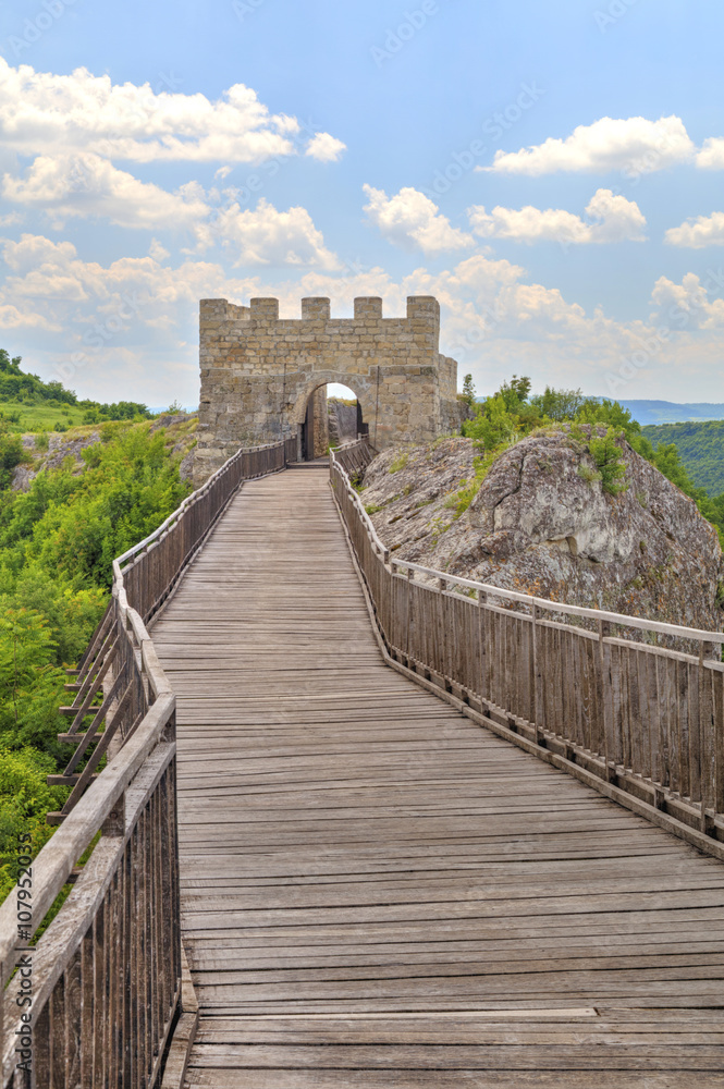 Stone walls and gate with wooden bridge of medieval fortress