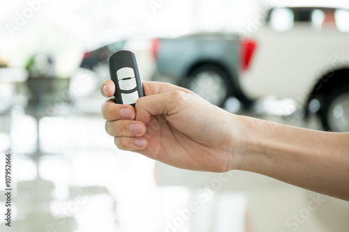 Human hands giving thumbs up with car key in car shoowroom