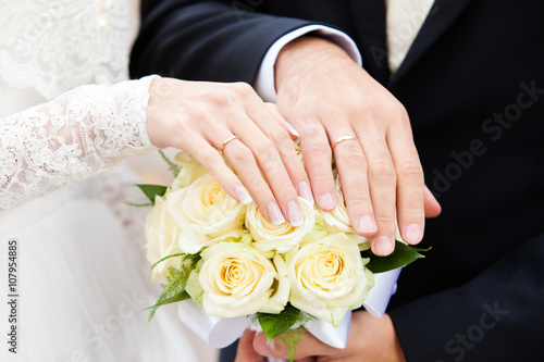 hands of groom and the bride on a yellow bouquet