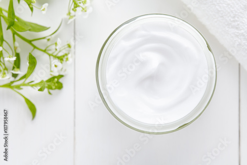 Cosmetic cream with herbal flowers healthy natural skincare product in glass jar on white background