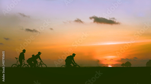 The silhouette of people cycling with blur orange light background concept of clam  selective focus the the silhouette