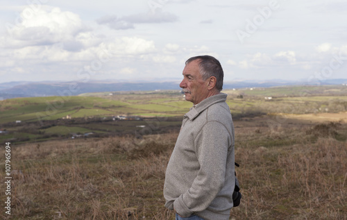 Portrait image of a mature man outdoors, looking out, over a view. © stephm2506