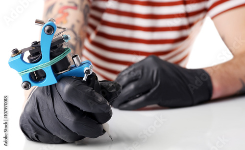 Tattoo master working in black medical gloves with tattoo machine, close up