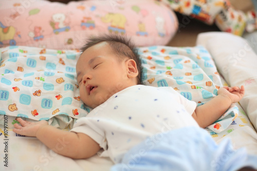 Cute asian newborn baby sleeping on bed