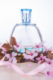 Women's perfume and pink cherry blossom. Sakura Branch and female perfumes on white background. Romantic Spring concept