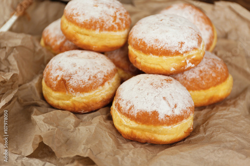 Delicious donuts with powdered sugar on parchment closeup