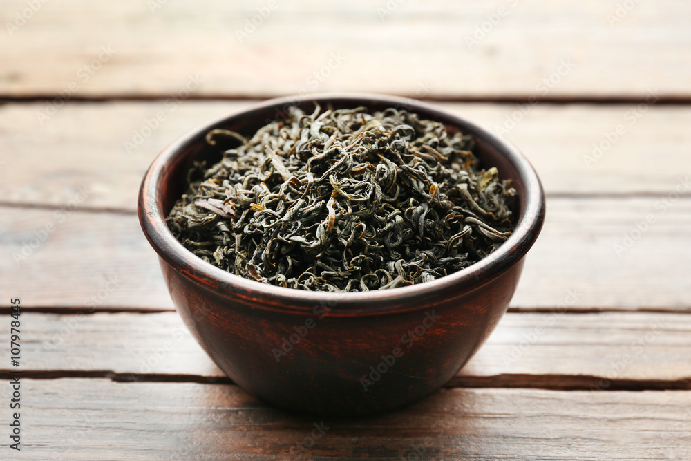 Fototapeta premium Green tea in a round bowl on wooden table, close up