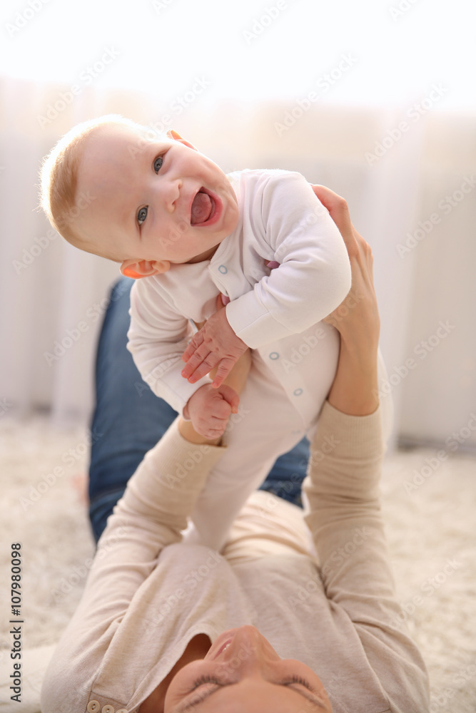 Woman playing with cute baby on the floor, close up Woman playing with cute baby on the floor, close up