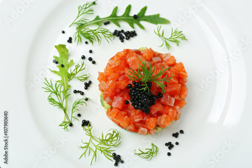 Delicious salmon tartare with black caviar on white plate