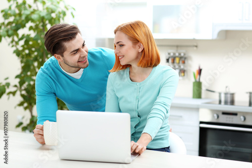 Young couple using laptop on the kitchen