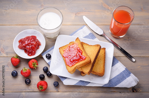 Bild auf Leinwand Sweet rusks, strawberry jam, milk and juice of blood oranges