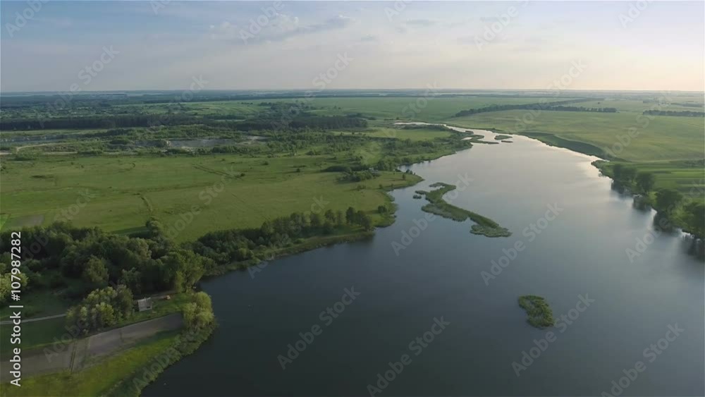 Aerial shot: Flying over river and fields. Clouds on background
Aerial shot: Flying over river and fields. Clouds on background