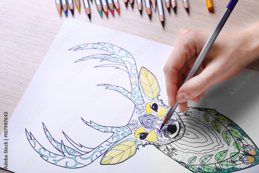 Fototapeta premium Female hand drawing with crayon in adult anti stress coloring closeup
