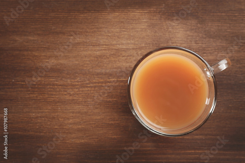 Tea with milk on wooden background.